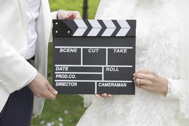 Noiva bonita feliz e noivo, mulher mantém a placa de palmas, placa de cinema
  - Foto, Imagem