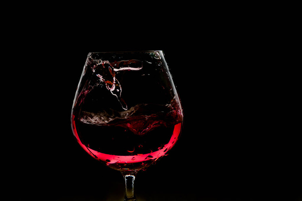 Всплеск вина в стакане на темном фоне
 - Фото, изображение