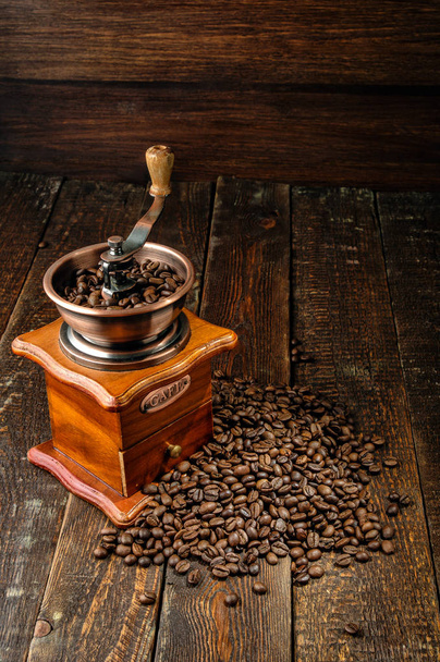 Coffee mill, kávé bab a sötét fa asztal - Fotó, kép