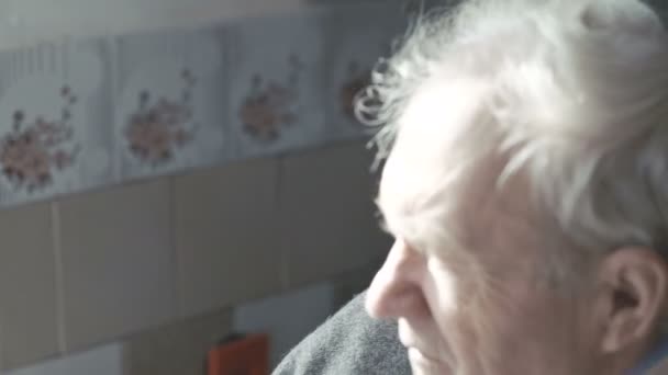 Portrait of old man sitting near the window and looking at camera 4K - Felvétel, videó