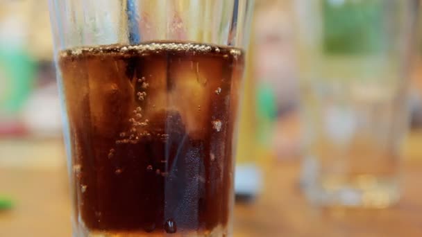 Pouring cola into a glass with ice on a table - Footage, Video