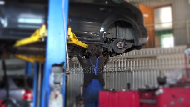 car mechanic worker repair suspension of lifted automobile at repair garage. - Footage, Video