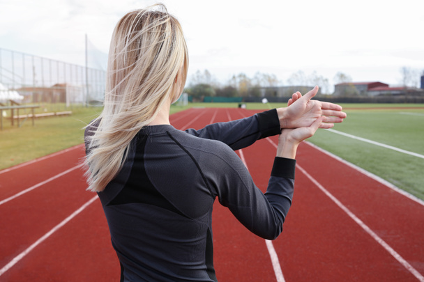 Fitness-Frau streckt die Arme vor dem Laufen oder Ausdauertraining im Freien. Joggen, Sport, Fitness, aktives Lifestylekonzept, Kältetraining - Foto, Bild