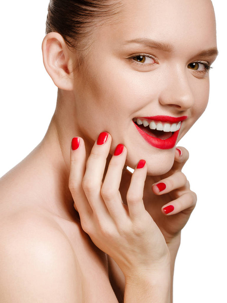 Jonge lachende vrouw met rode lippen en rode nagels, het aanraken van haar fa - Foto, afbeelding