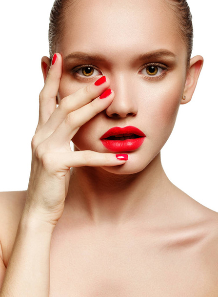 Young woman with red lips and red nails, touching her face - Foto, afbeelding