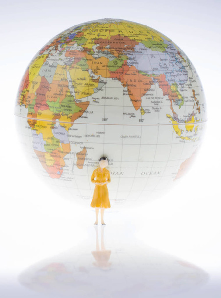 Маленький модельный глобус рядом с женской фигурой
 - Фото, изображение