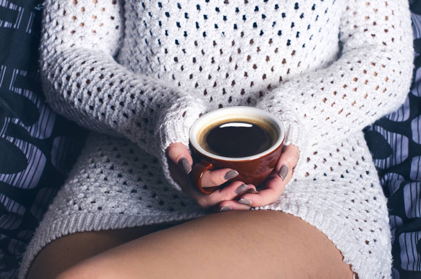 Detalle de la joven sexy. Mujer mantener una taza de café y sentado en una manta.. piernas desnudas. Ambiente hogareño
.  - Foto, Imagen