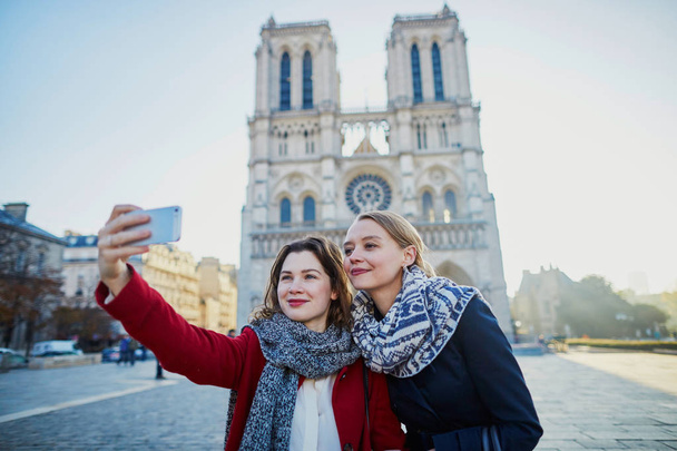 Twee jonge meisjes selfie te nemen in de buurt van Notre-Dame in Parijs - Foto, afbeelding