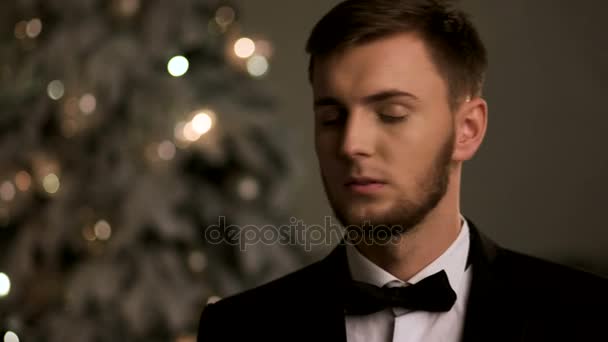 Красивый молодой человек в стильном костюме, позирует перед камерой во время Рождества
. - Кадры, видео