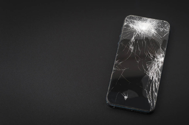 Smartphone mit kaputtem Bildschirm auf dunklem Hintergrund - Foto, Bild