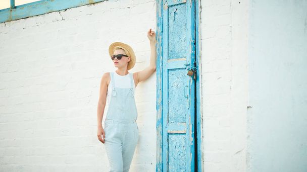 Pretty slim tan blonde stylish woman in straw hat and sunglasses posing - Fotó, kép