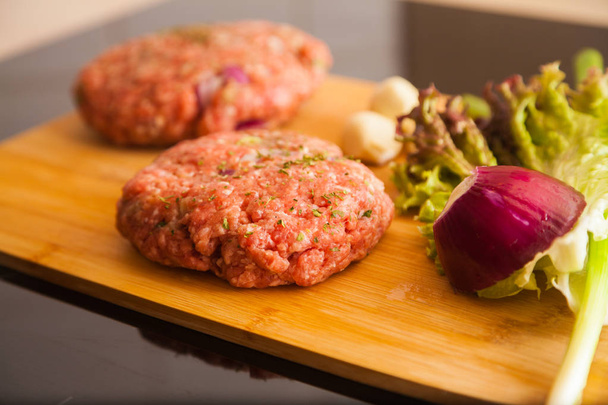 hamburguesa de carne cruda se encuentra en un tablero
 - Foto, Imagen