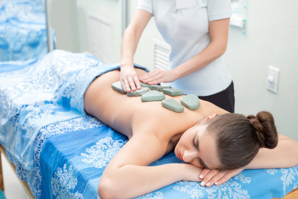 Pretty girl getting hot stone massage in spa salon - Φωτογραφία, εικόνα