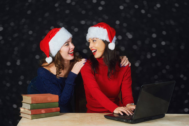 Two young girls in red Christmas hats Santa write a letter to Santa . Christmas eve . - Foto, imagen