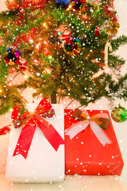 Karácsonyi ajándék doboz és hó hatállyal díszített karácsonyfa - Fotó, kép