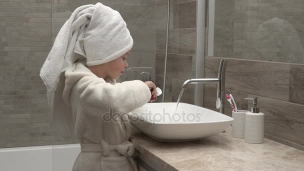 lány egy törölköző és fürdőköpeny, takarítás a fogak - Felvétel, videó
