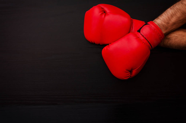 Two male hands in red boxing gloves on a black background in the corner of the frame, place for text - Photo, Image