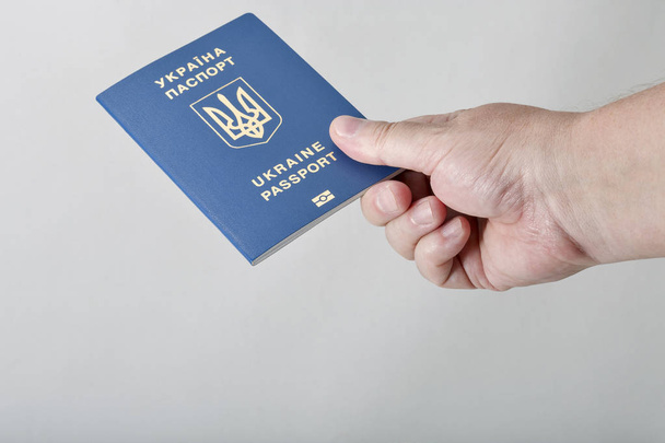 Mano sosteniendo pasaporte biométrico ucraniano contra fondo blanco
 - Foto, imagen