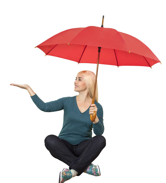 The girl with the red umbrella sits cross-legged, isolated on white background - 写真・画像