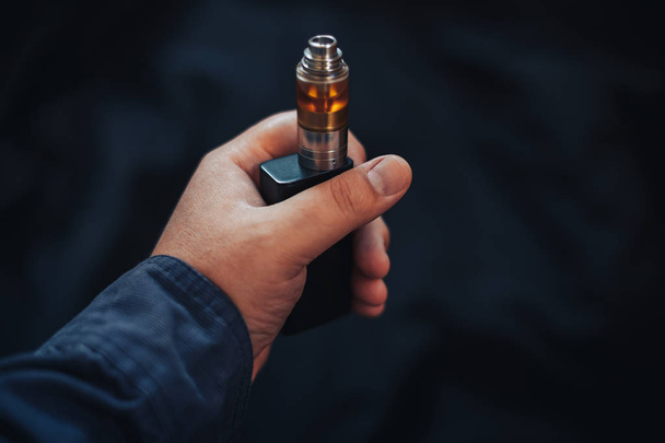 Vaping device in in the man's hand. Electronic cigarette, vape - Photo, Image