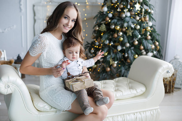 Mother and young son at home near Christmas tree - Фото, изображение