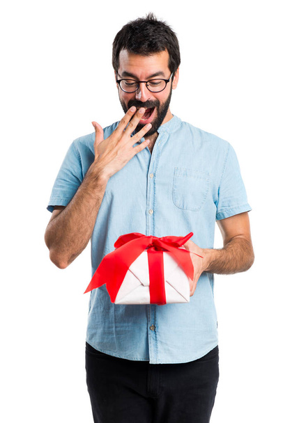 Handsome man with blue glasses holding a gift - Foto, imagen