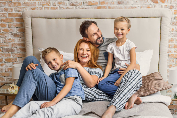 Happy family lying down on bed at home - Photo, image