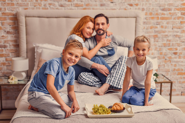 Happy family lying down on bed at home - Fotoğraf, Görsel