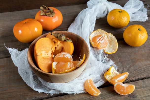 Cachi e mandarini freschi in ciotola
 - Foto, immagini