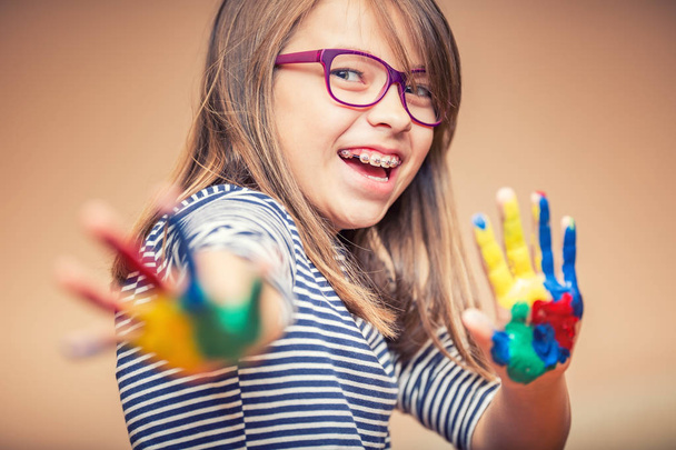 Portrait of a little pre-teen student girl showing painted hands. Toned Photo - 写真・画像