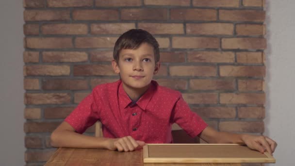 Flipchart Evet arka plan kırmızı tuğla duvar üzerinde yazı ile tutarak masada oturan çocuk. - Video, Çekim