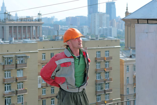 Man builder on the roof. City background - 写真・画像