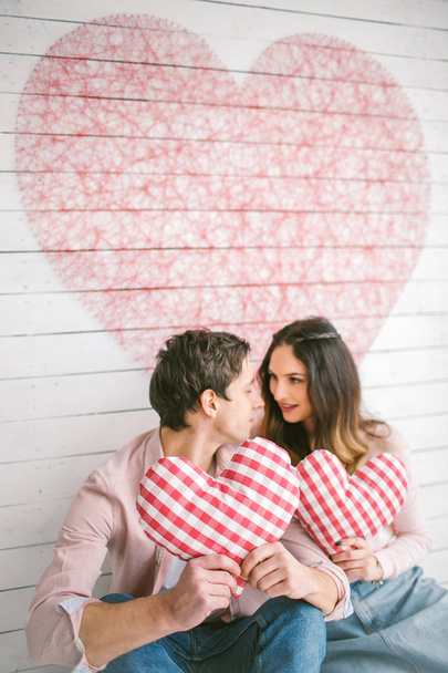 Young couple with heart-shaped pillows posing for love-story in  - Foto, Bild
