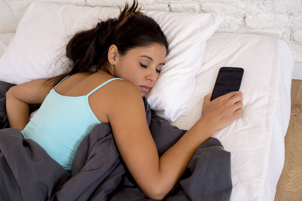 женщина спит в постели дома вместе с мобильным телефоном в интернет-зависимости сети
 - Фото, изображение