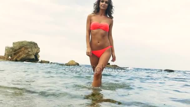 Krásný mladý model nosí červené plavky, pózuje na pláži. - Záběry, video