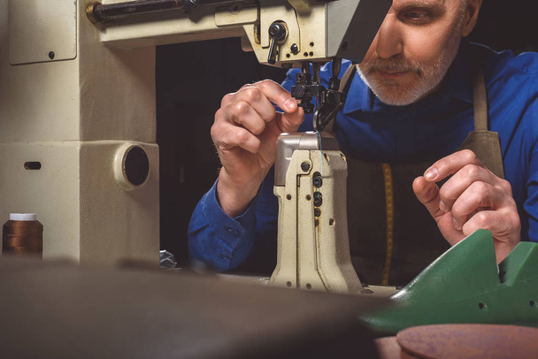 man preparing the tailoring machine for work - Фото, зображення