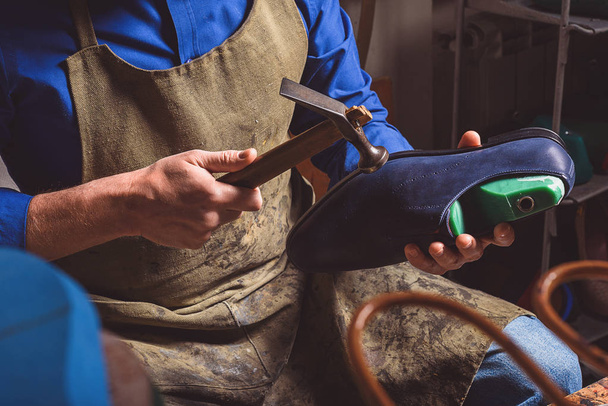 artisan holding a boot and hammer - Foto, Bild