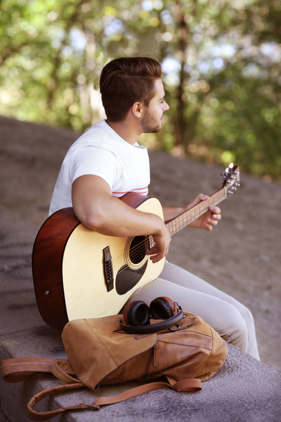 Handsome man playing acoustic guitar on street - Photo, Image