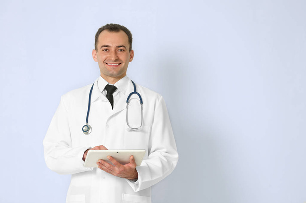 Doctor with tablet on color background - Foto, afbeelding