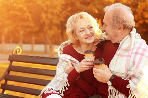 mature couple with coffee in autumn park - Фото, изображение