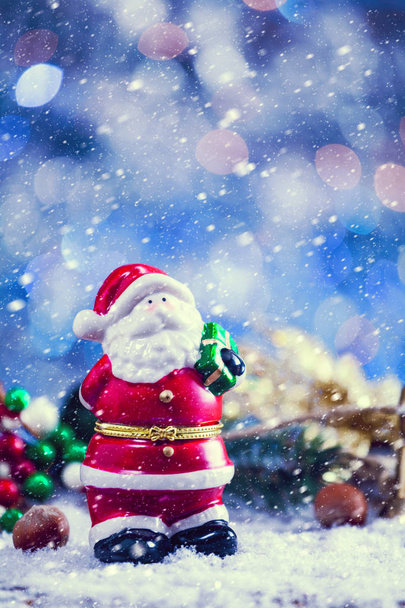 Neve caduta su mini statua del giocattolo di Babbo Natale con Jingle Bells. Filtro Vintage applicato
. - Foto, immagini