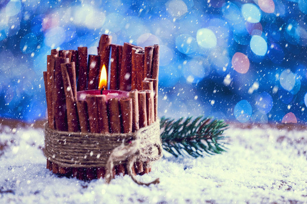 Schnee fällt auf rote Zimtstangen Weihnachtskerzen brennen. Vintage-Filter aufgetragen. - Foto, Bild
