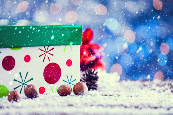 Schnee fällt auf flache grüne Weihnachtsgeschenkbox mit Dekoration Vintage-Filter aufgetragen. - Foto, Bild