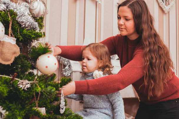 Mom and daughter decorating Christmas tree - Фото, зображення