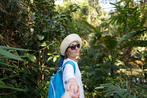 Seguitemi. Concetto di viaggio. Vista posteriore di giovane donna con zaino all'aperto alla scoperta della giungla tenendo la mano del fidanzato
. - Foto, immagini