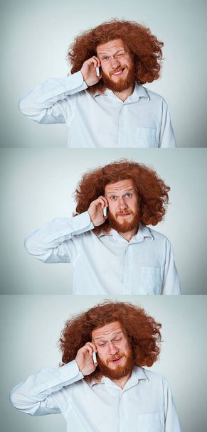 Portrait of puzzled man talking on the phone  a gray background - Photo, Image