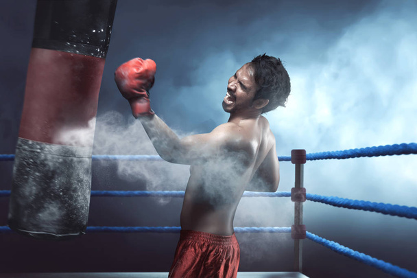 Asian man boxer practicing with punching bag - Foto, Imagen