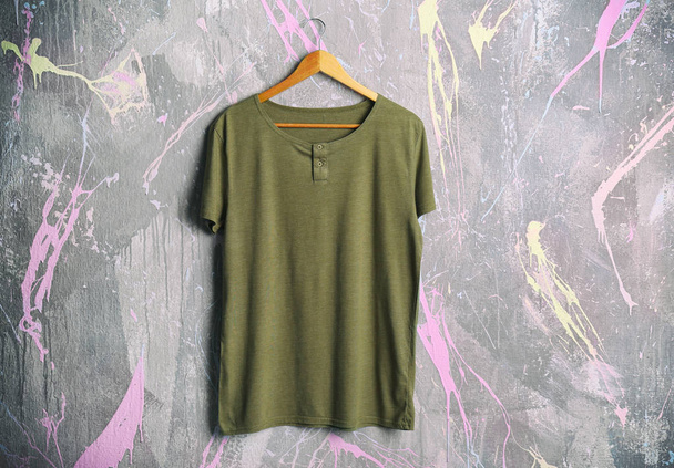 green t-shirt against grunge wall - Фото, изображение