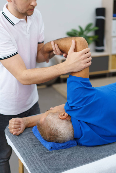 Physiotherapist doing massage to elderly man - Valokuva, kuva