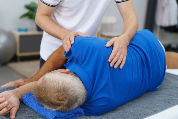 Physiotherapist doing massage to elderly man - 写真・画像